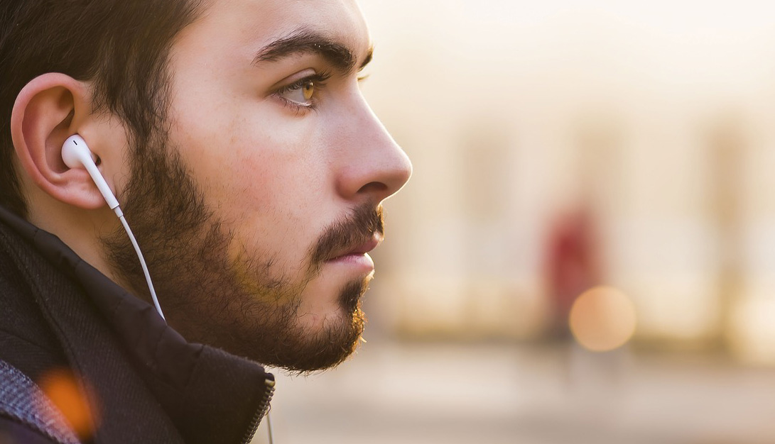 man with short beard with earphones in his ears