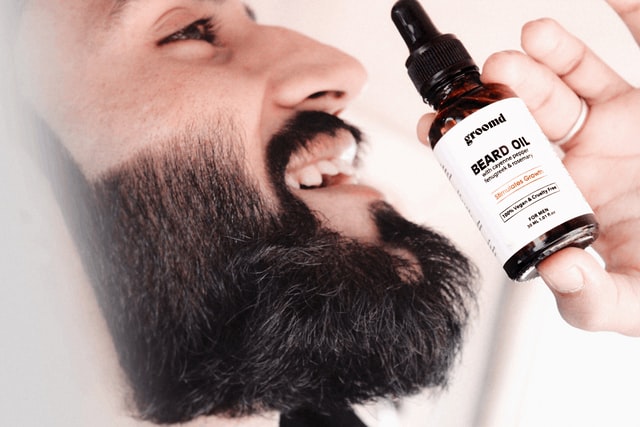 man applying jojoba oil to beard