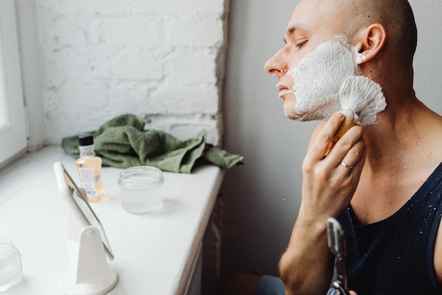 man shaving his face to remove a beard shadow