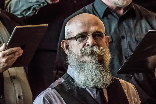 man with bald head and curled mustache with grey beard